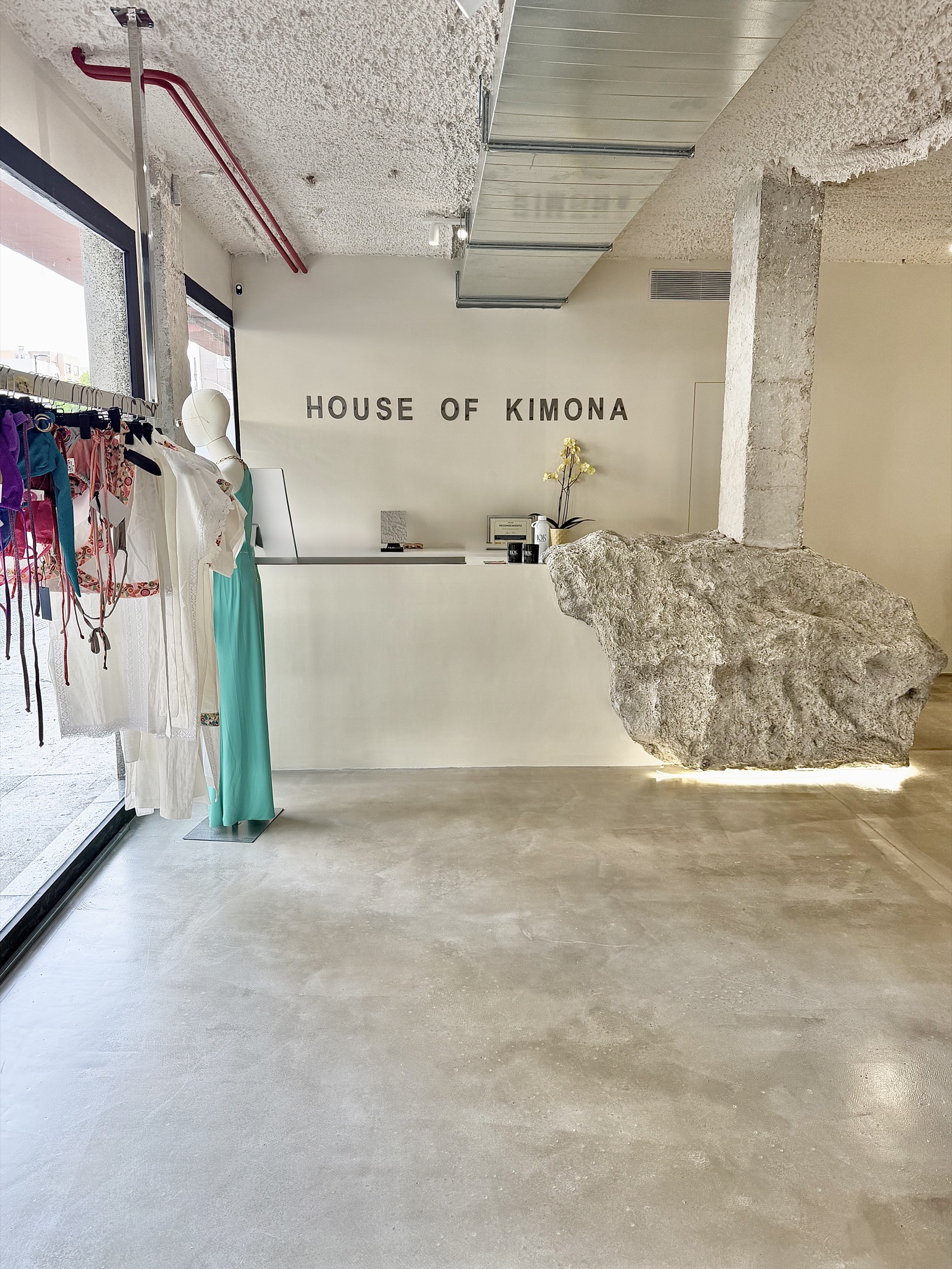 Interior de la tienda House of Kimona en Ibiza, con el mostrador de piedra y el nombre de la casa